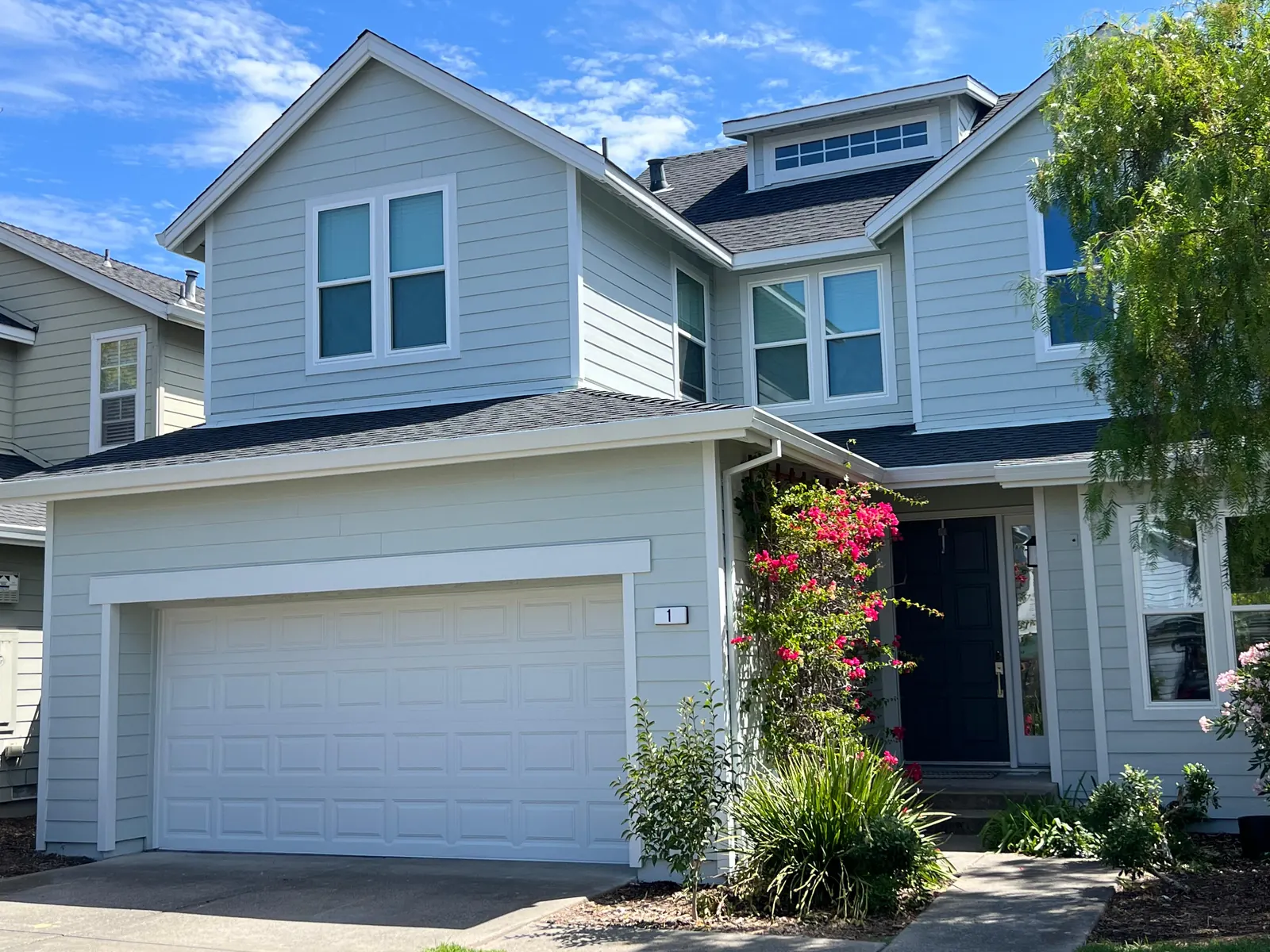 Two-story home with light blue lap siding, white trim, and a white garage door
