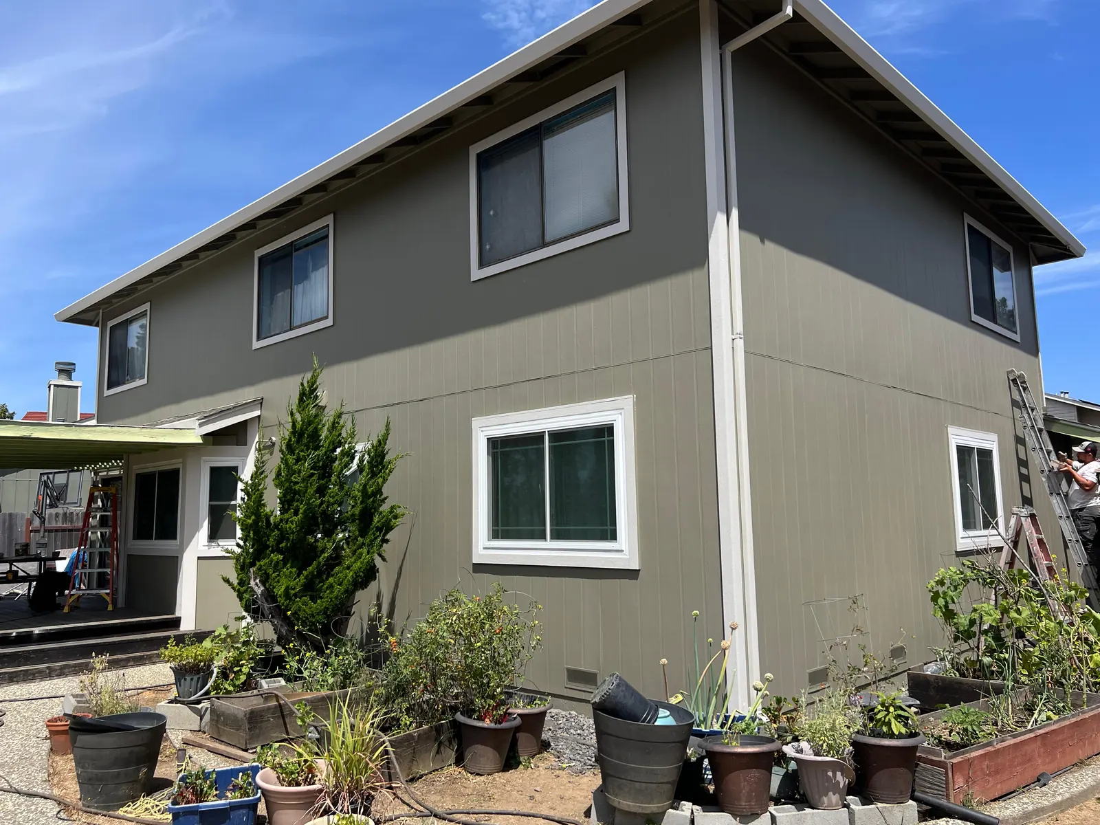JTM Remodeling crew working on the gray siding of a two-story home