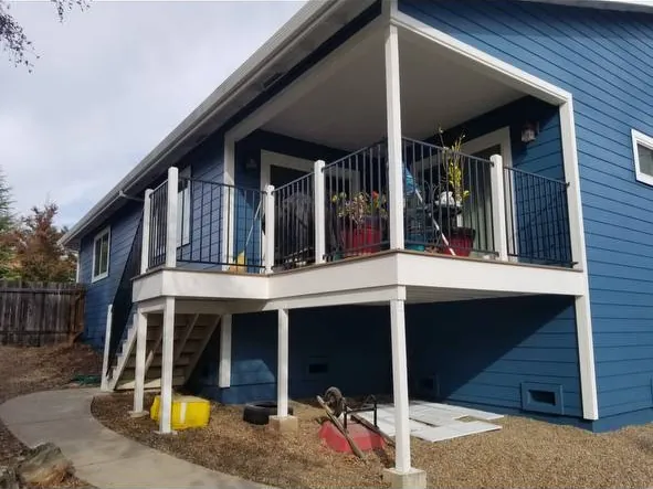 Home with fresh blue exterior paint, white trim, and a covered deck